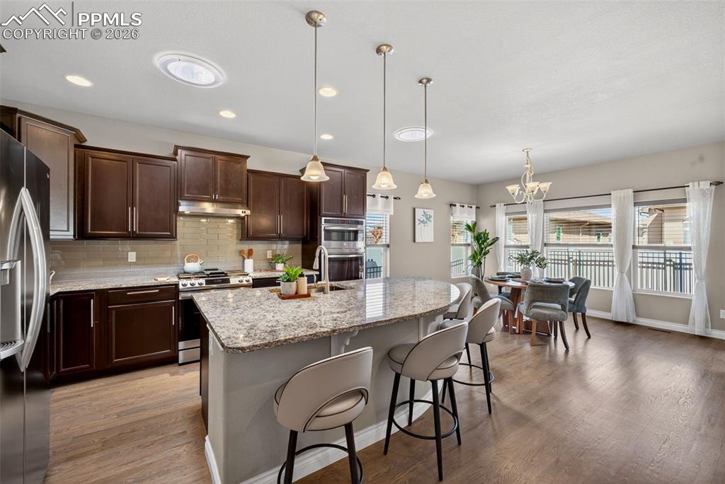 Image 13 of 34: Living area featuring vaulted ceiling, suspended lighting, wood finished fl