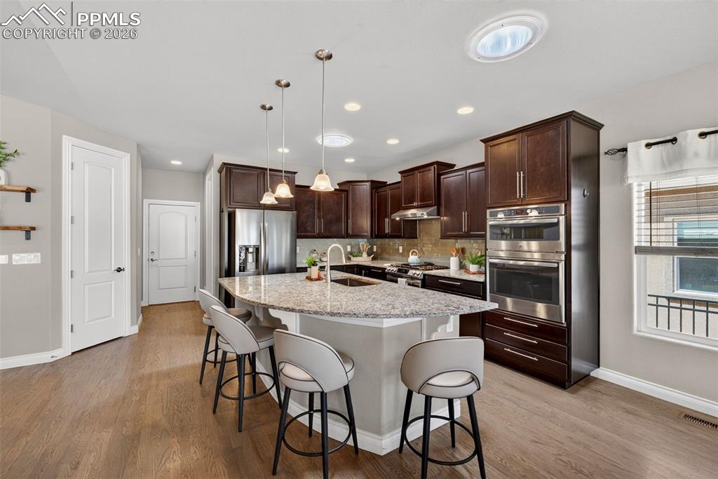Image 15 of 34: Dining space featuring wood finished floors and hanging lights