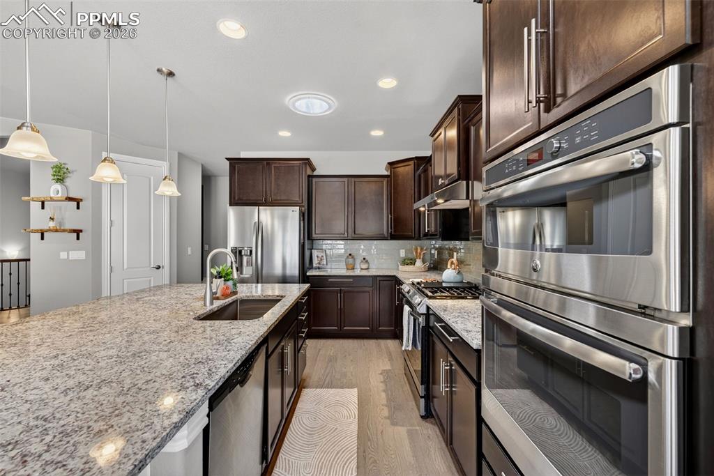 Image 16 of 34: Kitchen featuring stainless steel appliances, light stone countertops, ligh