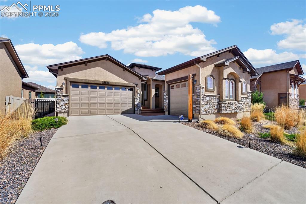 Image 2 of 34: View of front facade featuring stone siding, a garage, driveway, and stucco