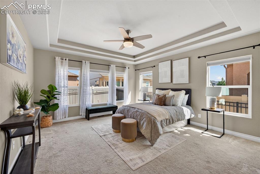 Image 20 of 34: Carpeted bedroom featuring a ceiling fan and a tray ceiling