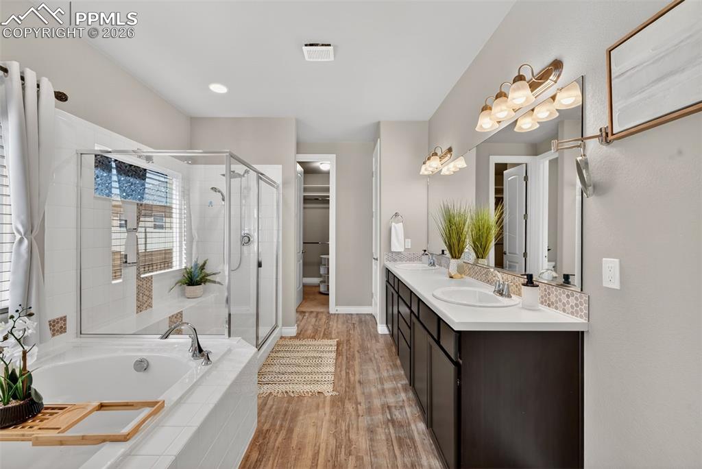 Image 22 of 34: Full bathroom with double vanity, a spacious closet, a bath, a shower stall
