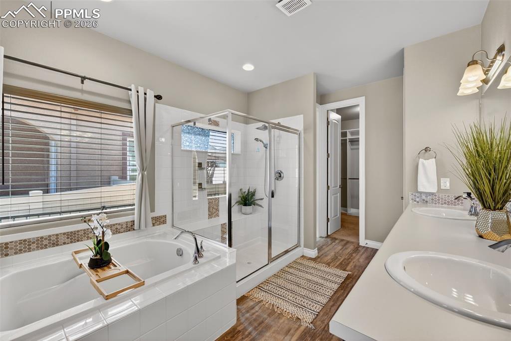Image 23 of 34: Full bathroom with a walk in closet, double vanity, a shower stall, dark wo