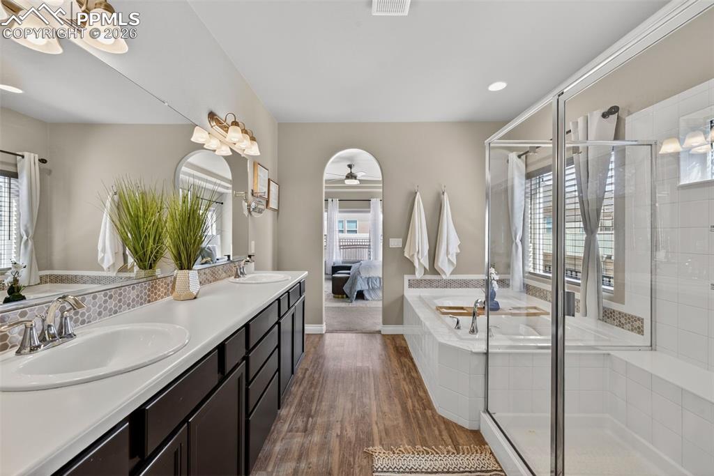 Image 24 of 34: Ensuite bathroom with a garden tub, a stall shower, double vanity, dark woo