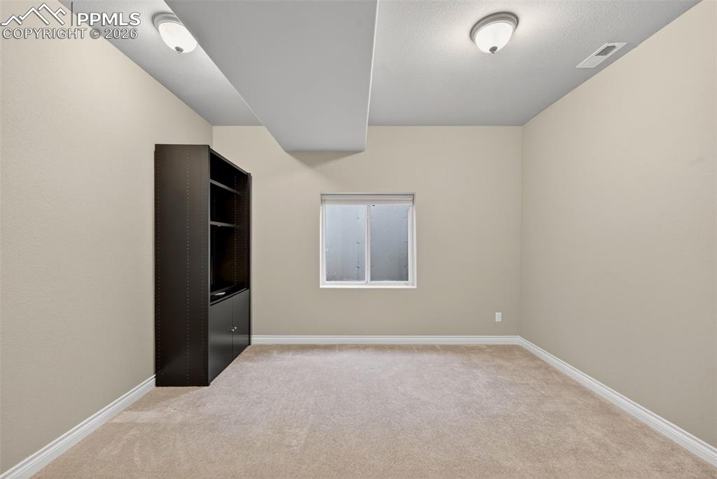 Image 31 of 34: Empty room with light colored carpet and baseboards