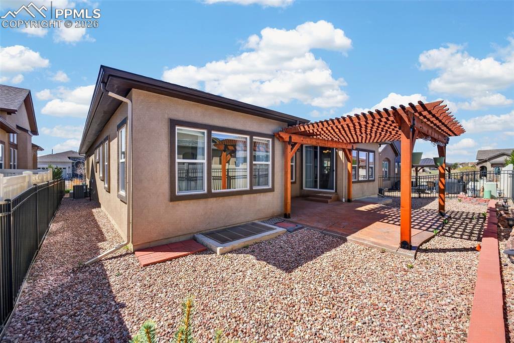 Image 33 of 34: Back of property with stucco siding, a pergola, a fenced backyard, and a pa