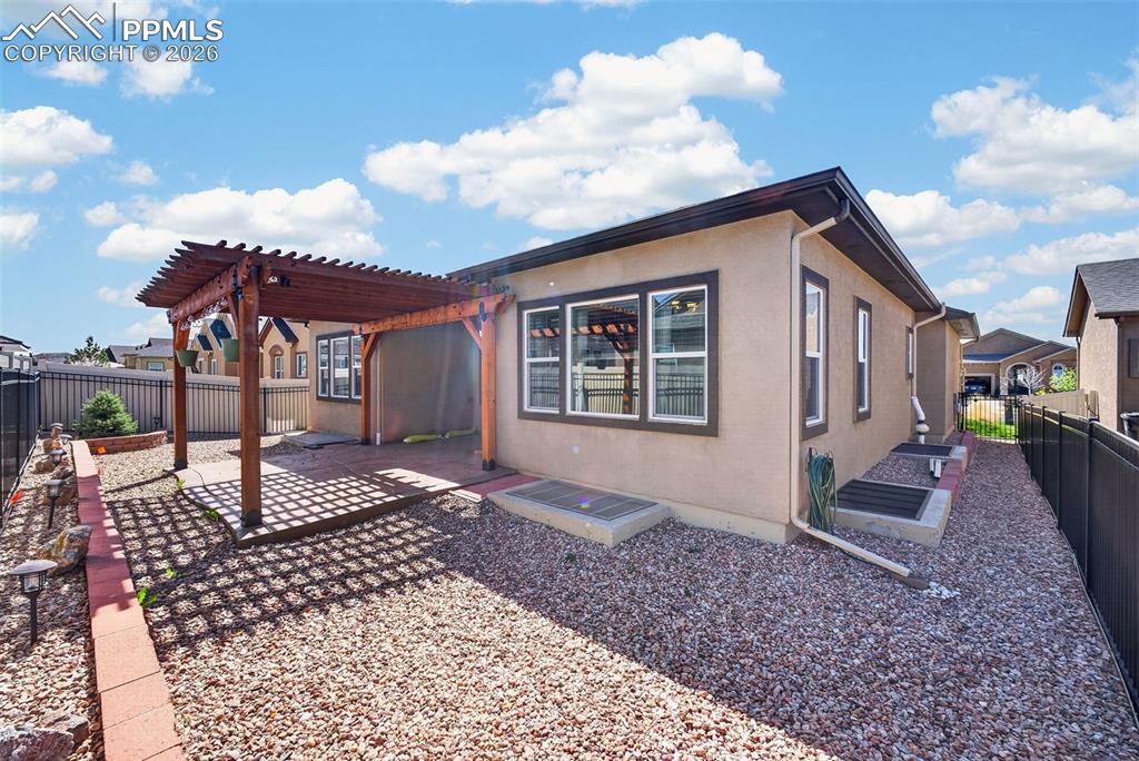 Image 34 of 34: Back of house featuring a fenced backyard, a patio area, and a pergola