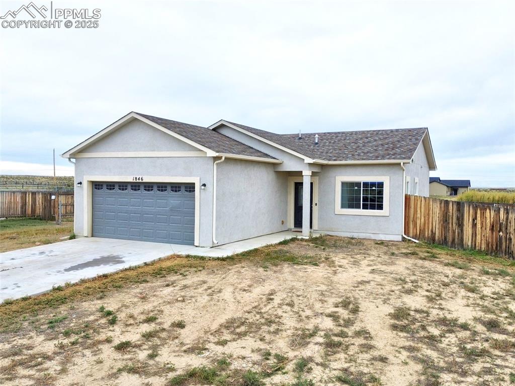 Caption: Ranch-style home with stucco siding, concrete driveway, a garage, and a shingled roof