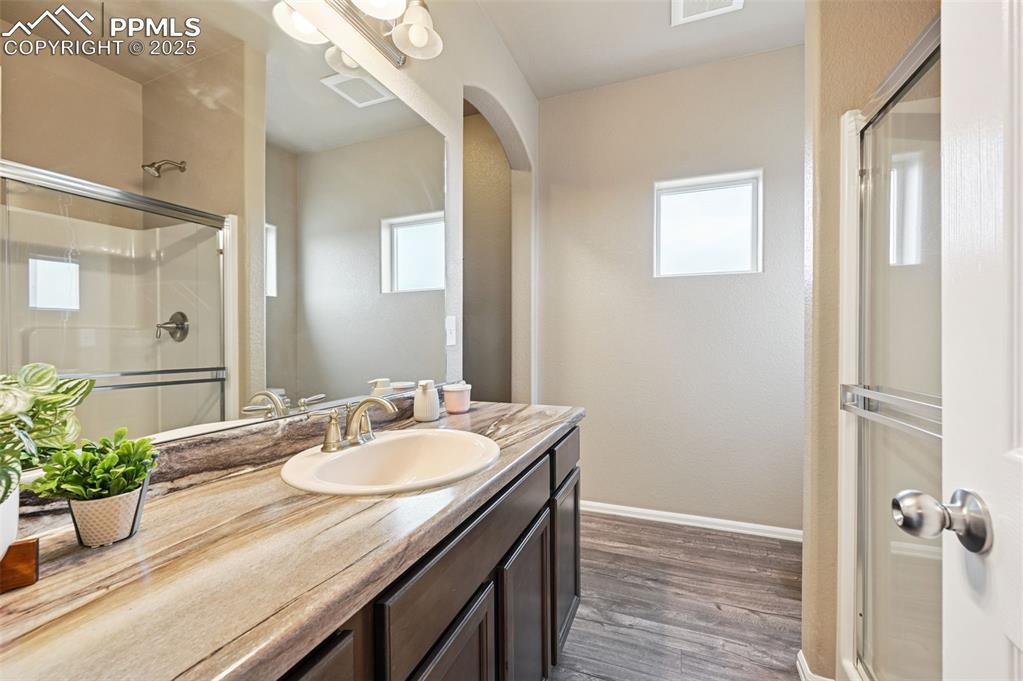 Image 14 of 29: Bathroom with vanity, a shower stall, and dark wood-style flooring