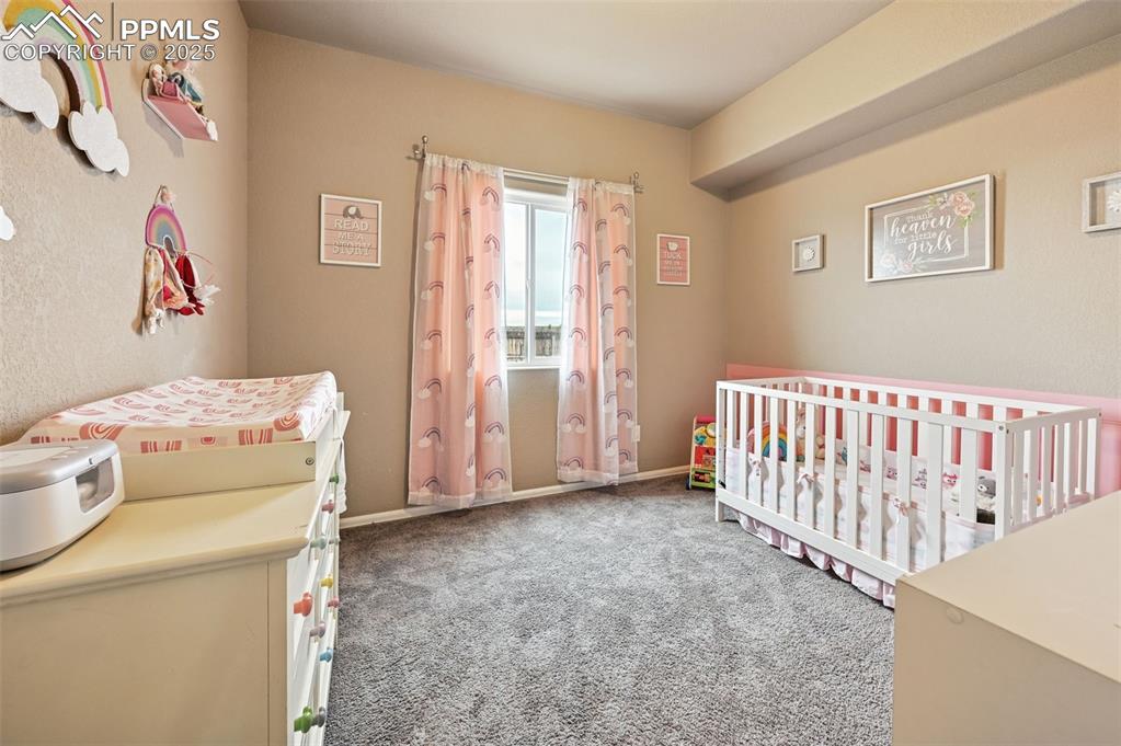 Image 16 of 29: Bedroom with a nursery area and carpet floors