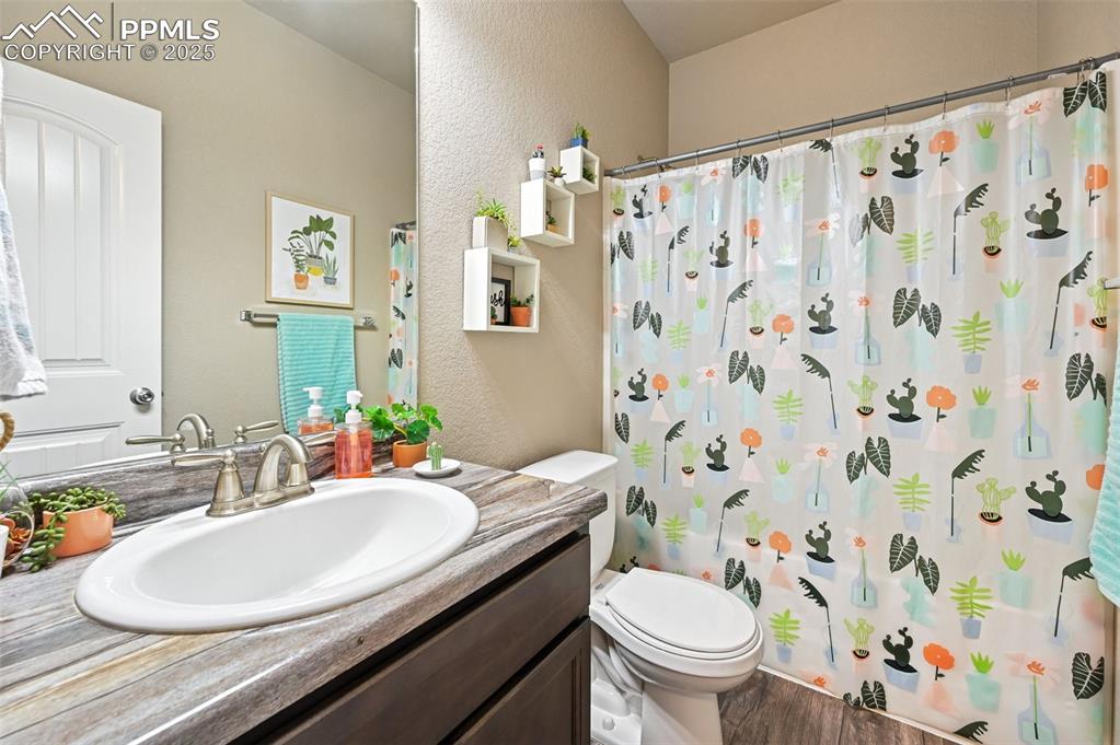 Image 20 of 29: Full bathroom featuring vanity, a textured wall, a shower with shower curta