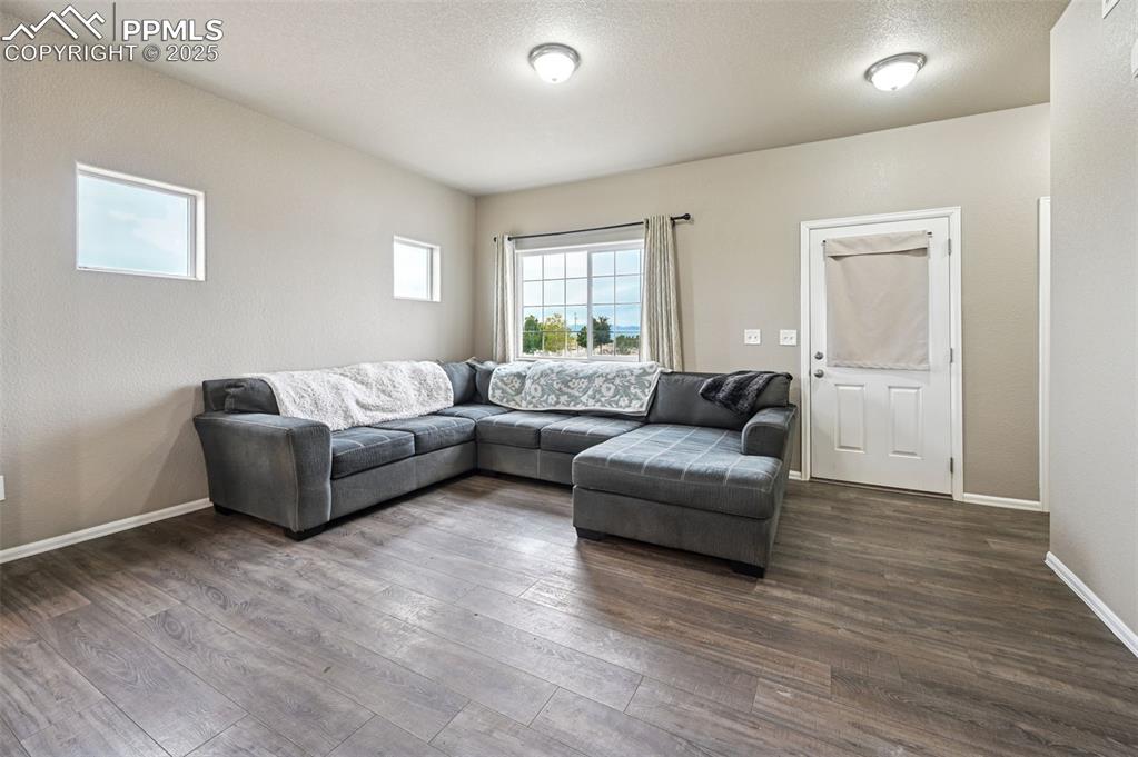 Image 3 of 29: Living area with dark wood-style flooring and a textured ceiling