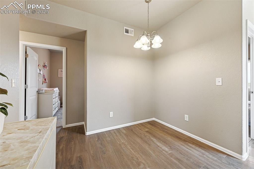 Image 9 of 29: Unfurnished dining area with dark wood-style floors, a chandelier, and a te
