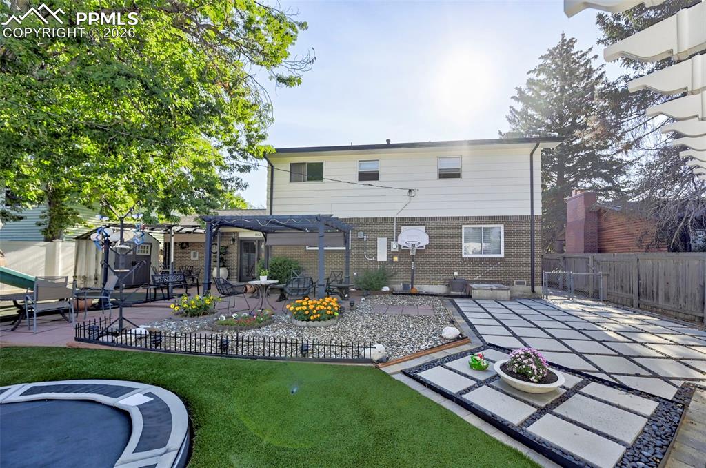 Image 10 of 46: Rear view of house featuring a pergola, a fenced backyard, and a patio