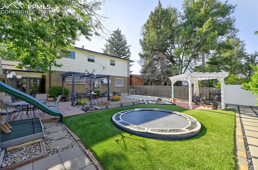 Image 11 of 46: Fenced backyard featuring a pergola, a patio, and a playground