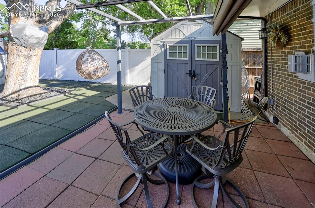 Image 14 of 46: Fenced backyard featuring a shed, a patio, outdoor dining space, and a perg