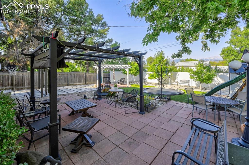 Image 15 of 46: Fenced backyard with a pergola, a patio, and a playground