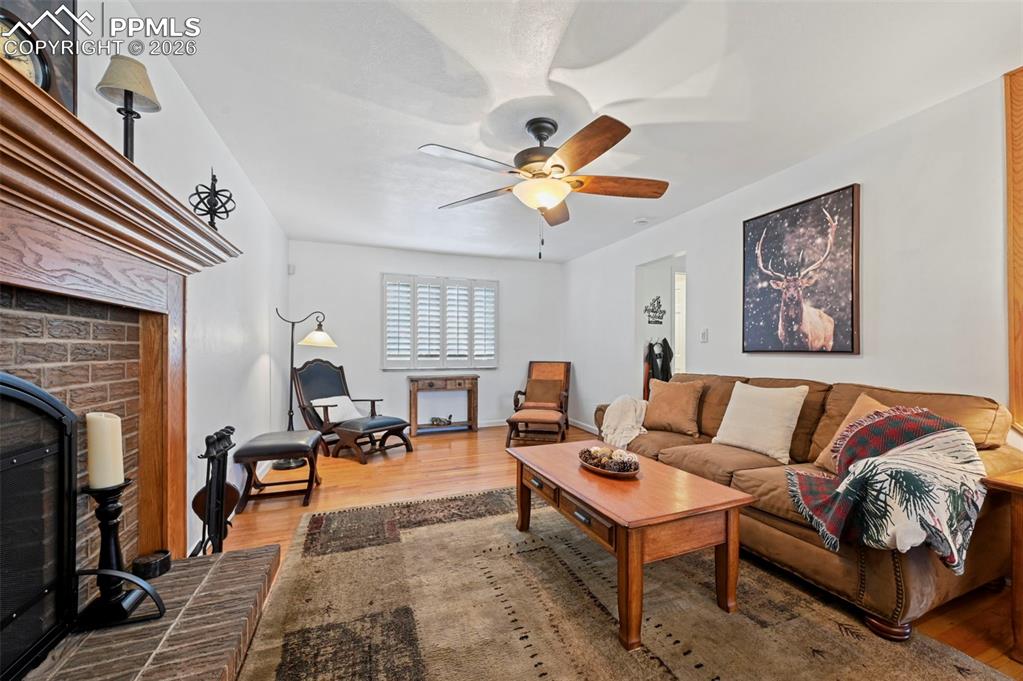 Image 18 of 46: Living room featuring a brick fireplace, light wood-style floors, and ceili