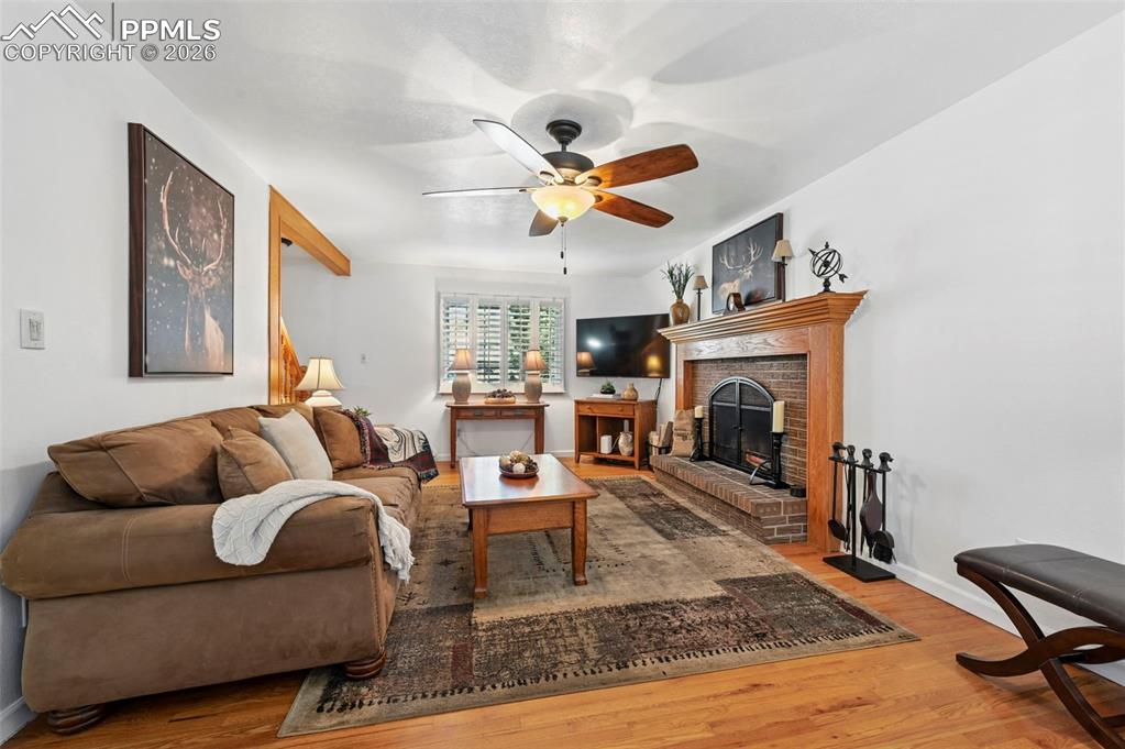 Image 20 of 46: Living room featuring light wood-style floors, ceiling fan, and a fireplace