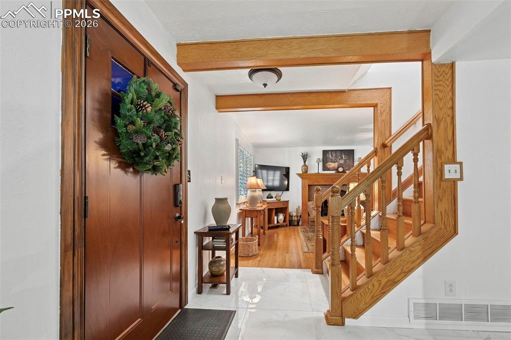 Image 23 of 46: Entrance foyer with beamed ceiling and a fireplace
