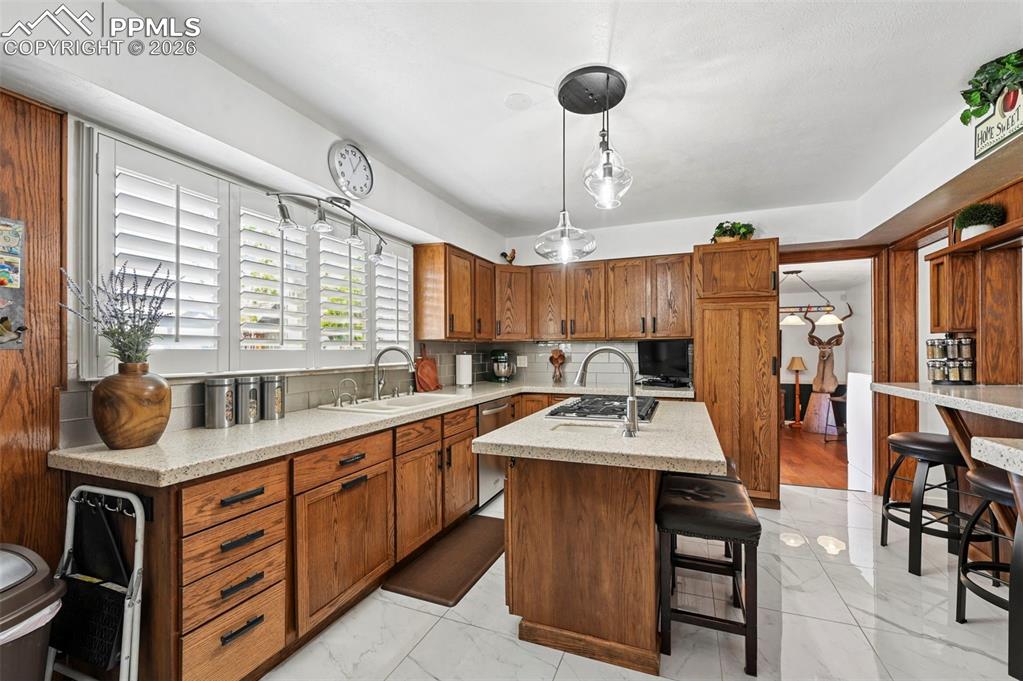 Image 29 of 46: Kitchen featuring a kitchen island with sink, wood finish cabinetry, light 