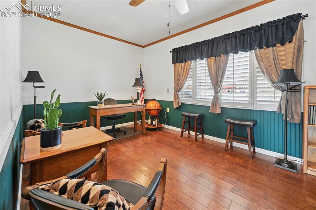 Image 32 of 46: Office space with a wainscoted wall, wood-type flooring, ceiling fan, and c