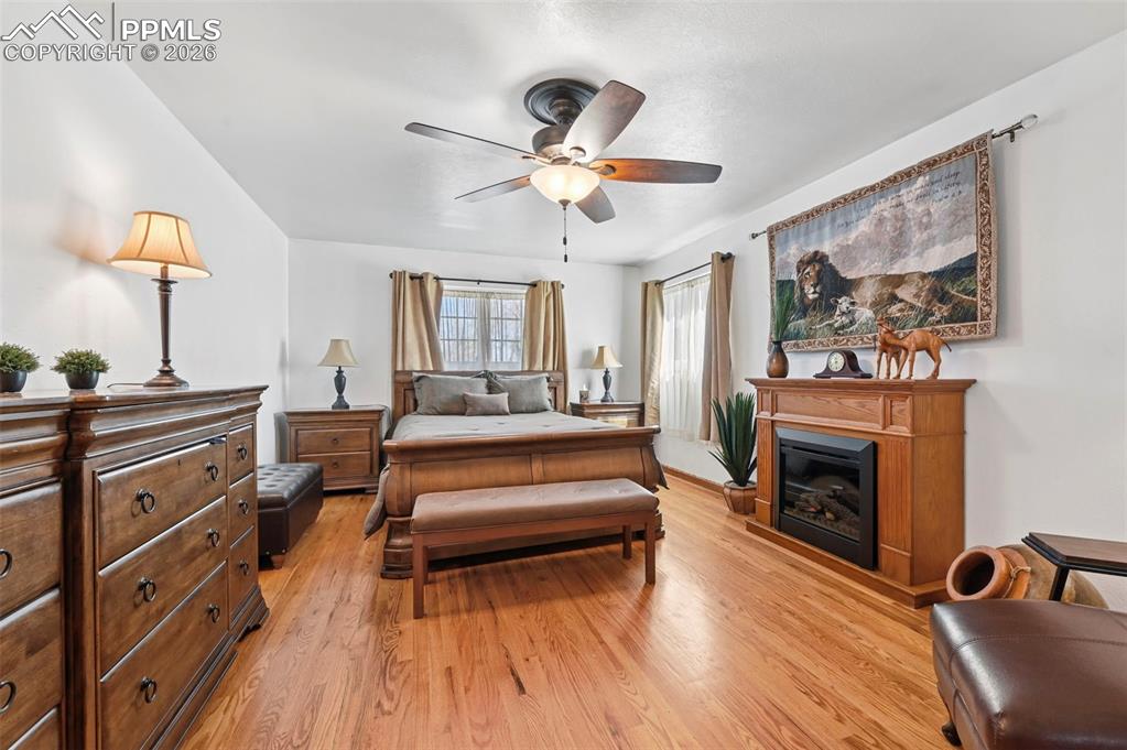 Image 34 of 46: Bedroom with light wood-style floors, a glass covered fireplace, and ceilin