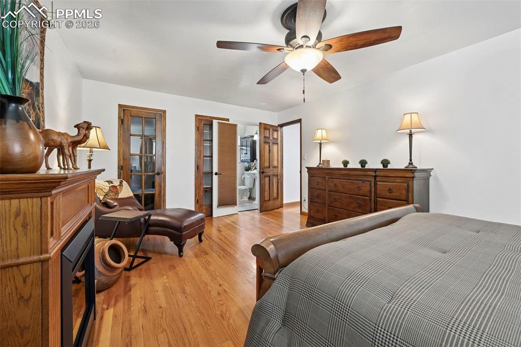 Image 36 of 46: Bedroom featuring light wood-type flooring, a ceiling fan, and ensuite bath