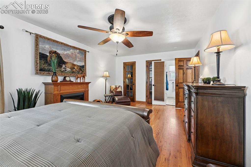 Image 37 of 46: Bedroom featuring light wood-style flooring, ceiling fan, a fireplace, and 