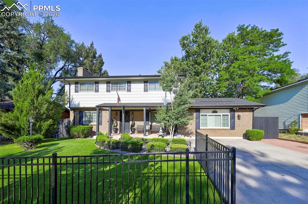 Image 4 of 46: View of front facade featuring a fenced front yard, brick siding, a chimney