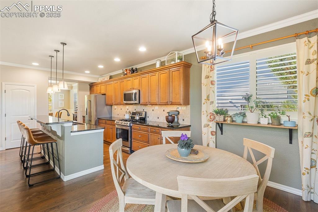 Image 11 of 46: Dining space with ornamental molding, dark wood-style floors, recessed ligh