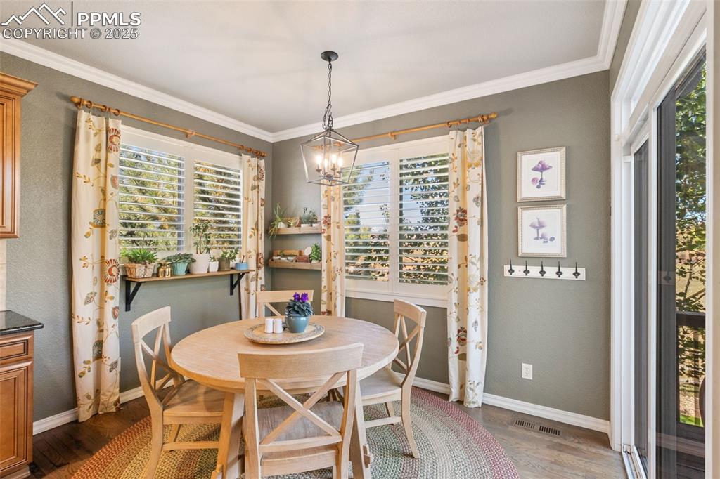 Image 12 of 46: Dining space with a chandelier, dark wood-type flooring, ornamental molding