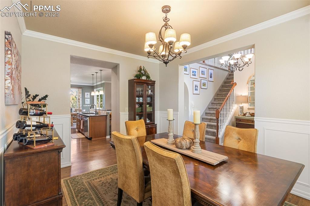 Image 15 of 46: Dining room with stairs, wainscoting, crown molding, a decorative wall, and