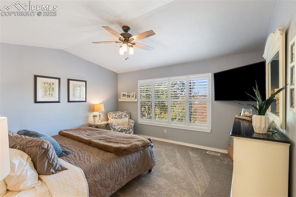 Image 21 of 46: Carpeted bedroom with lofted ceiling and a ceiling fan