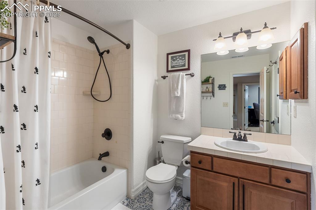 Image 32 of 46: Bathroom featuring vanity, shower / tub combo with curtain, tile patterned 