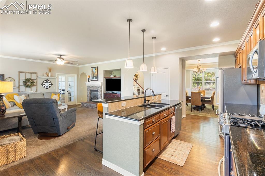 Image 9 of 46: Kitchen with a breakfast bar area, brown cabinetry, dark stone counters, cr