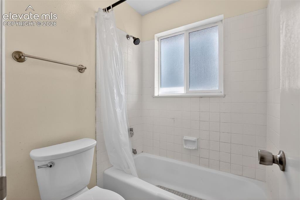 Image 17 of 28: Bathroom featuring a shower-tub combination, white ceramic tile surround, a