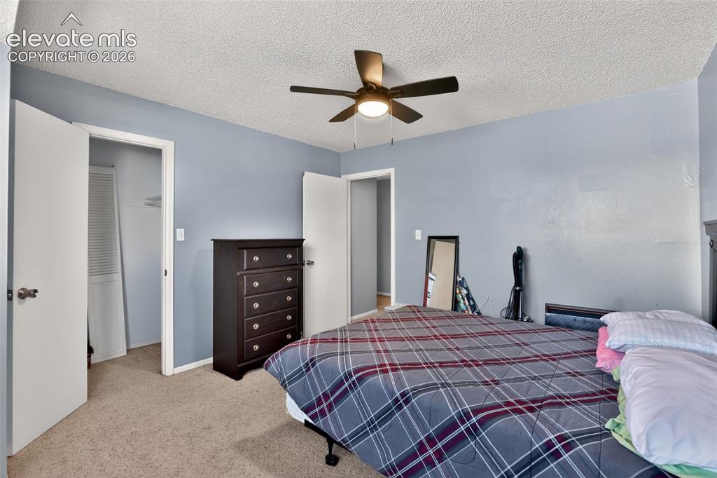 Image 19 of 28: Carpeted bedroom featuring a dark-toned ceiling fan with integrated lightin