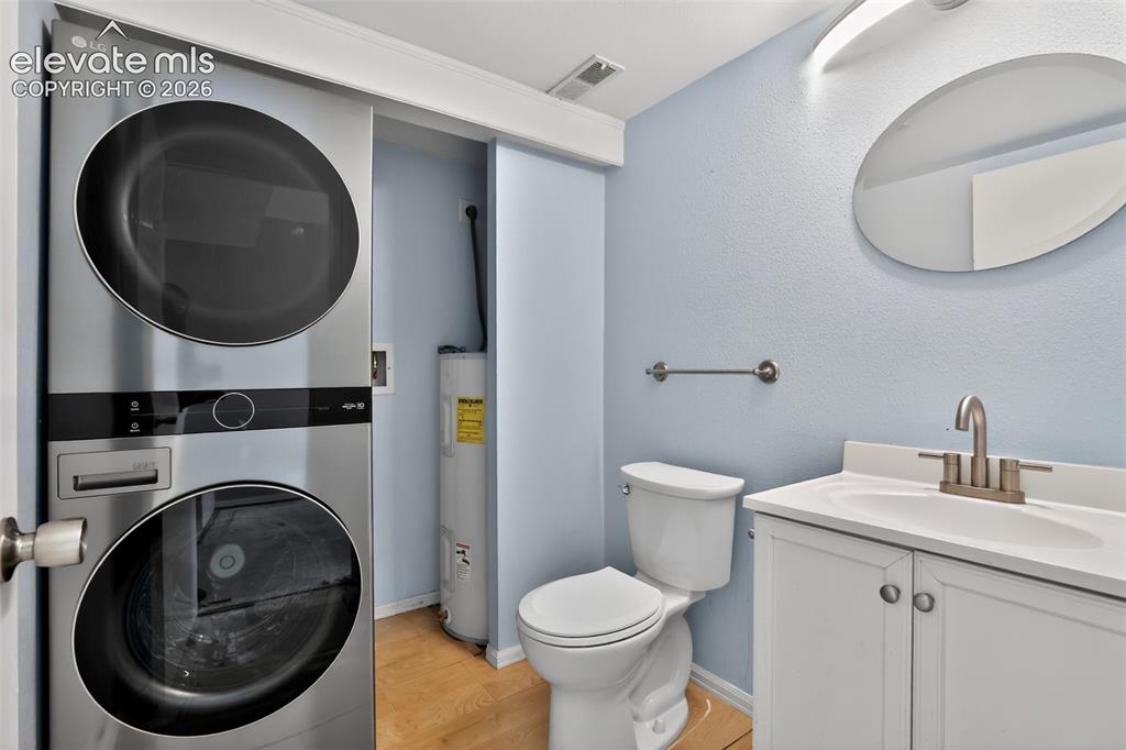 Image 20 of 28: Compact laundry area featuring a stacked washer and dryer unit within a clo
