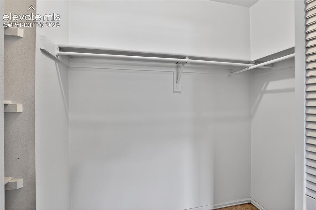 Image 21 of 28: White-painted closet with integrated shelving and hanging rods