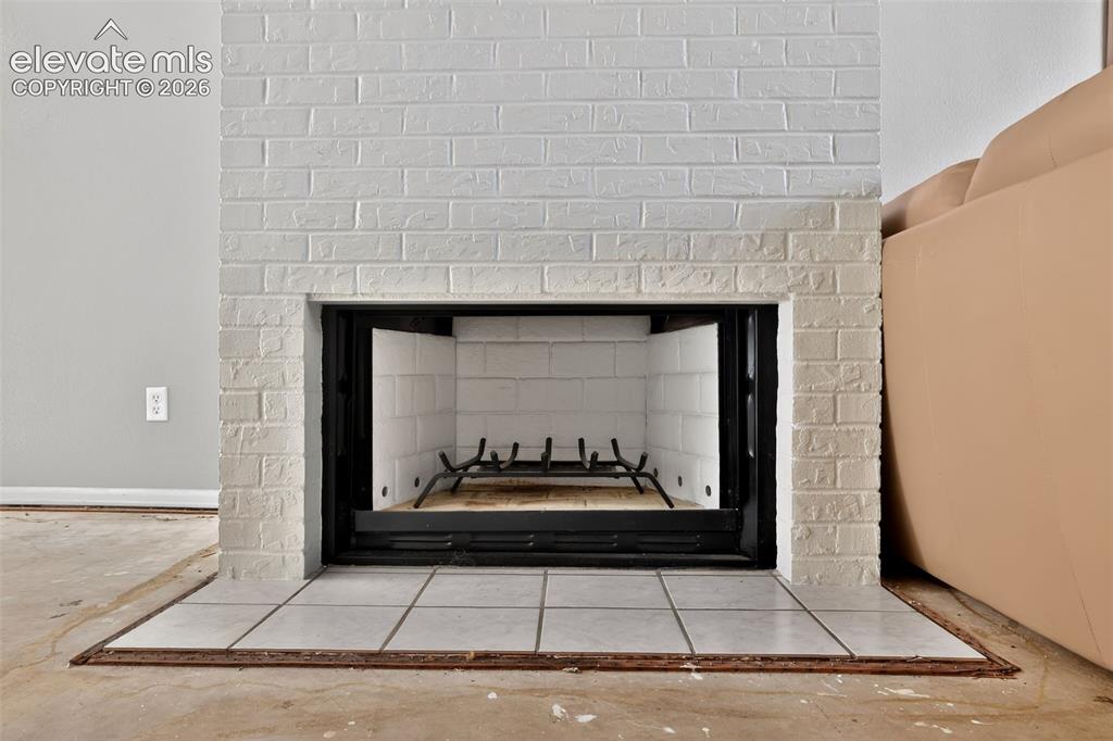 Image 23 of 28: White brick fireplace with a black metal firebox and white tile hearth