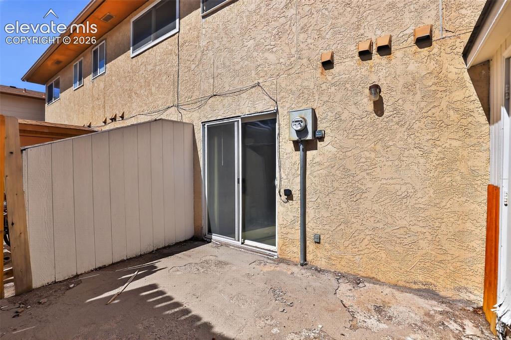 Image 24 of 28: Ground-level patio area featuring a concrete surface and stucco exterior