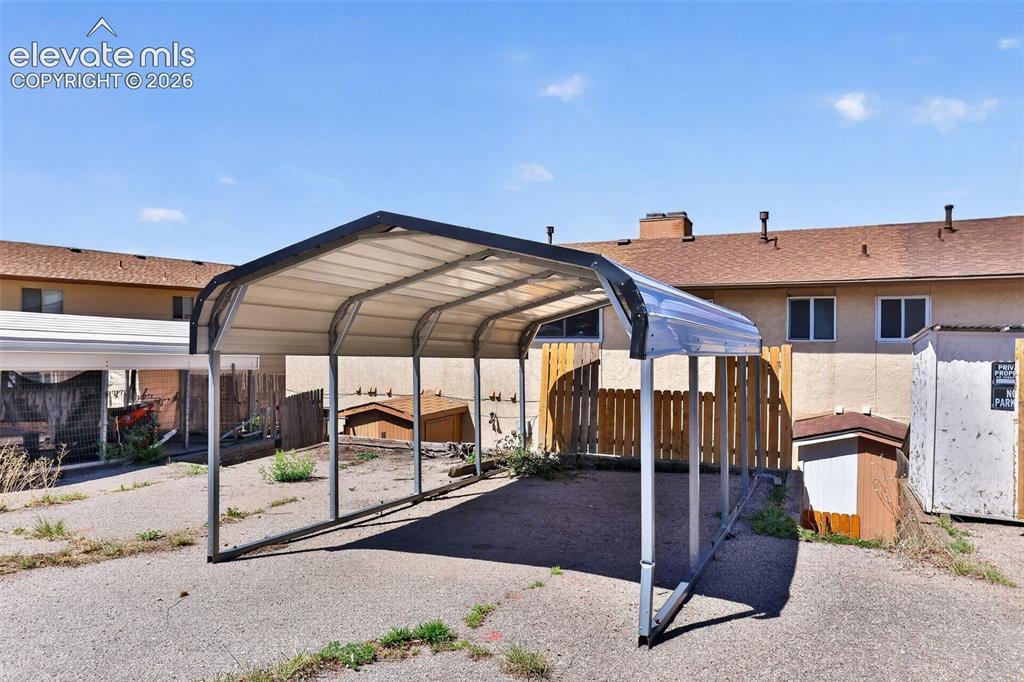 Image 26 of 28: Covered parking structure with a metal frame and corrugated roof