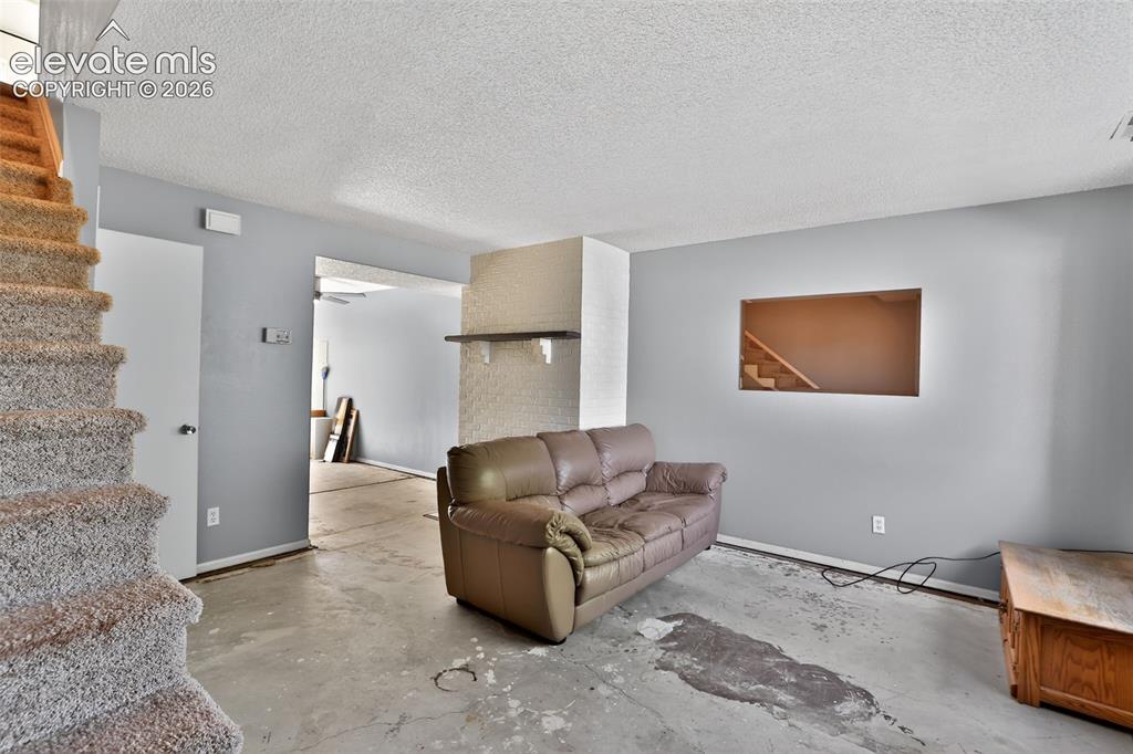 Image 3 of 28: Carpeted staircase with light wood handrail, textured ceiling, and a wall c