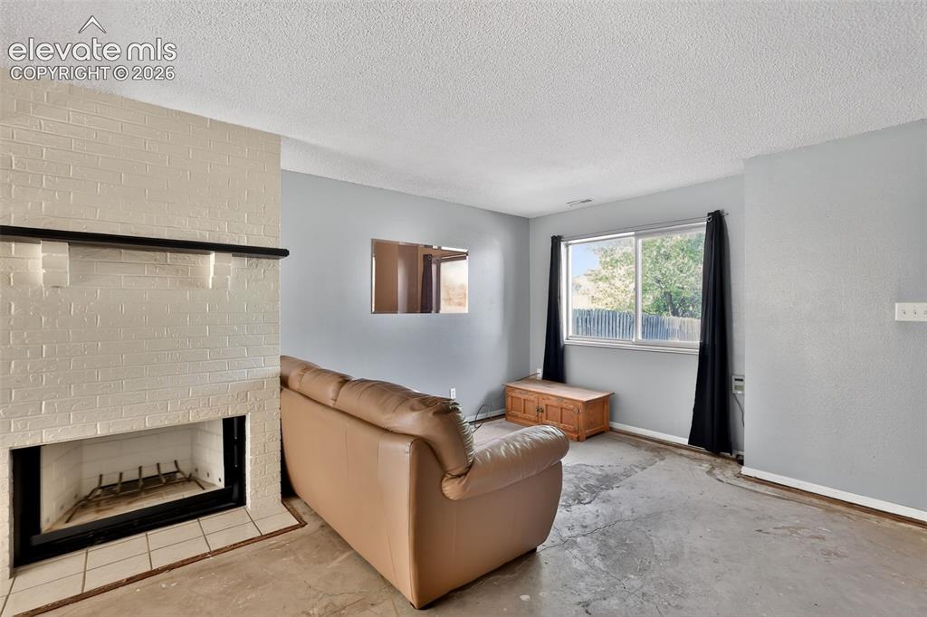 Image 5 of 28: Living area featuring a painted brick fireplace with a black mantel, a larg