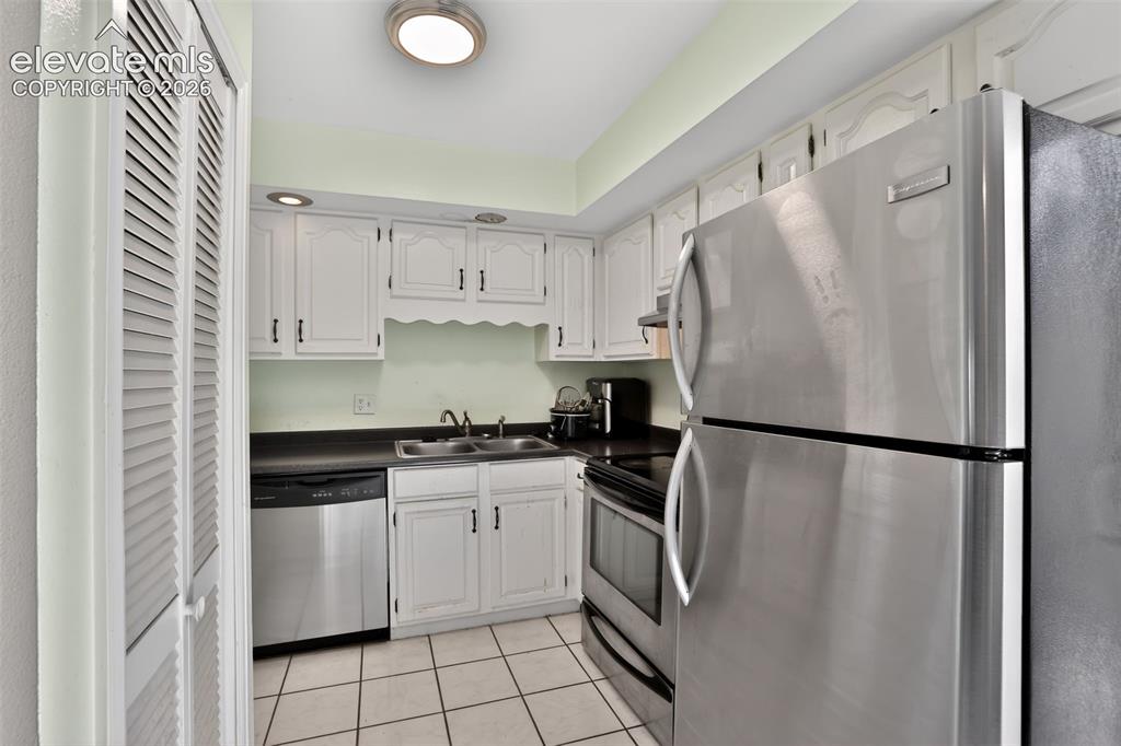 Image 9 of 28: Kitchen featuring stainless steel appliances, white cabinetry, dark counter
