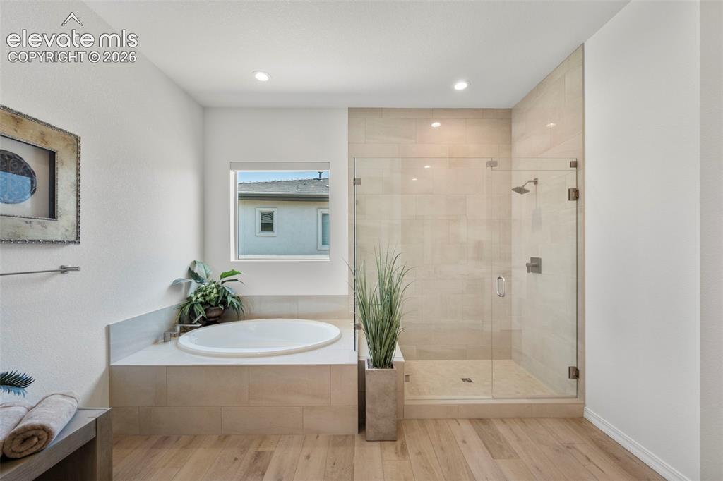 Image 19 of 50: Recessed lighting illuminates the soaking tub and walk-in shower with clear