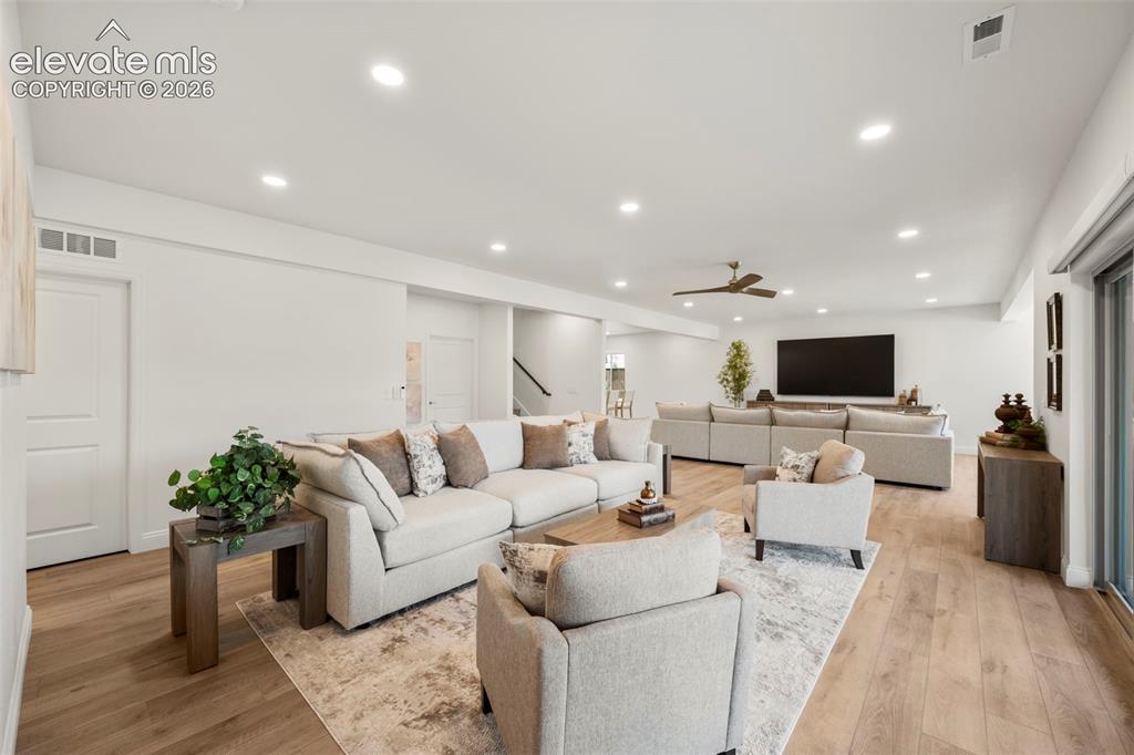 Image 27 of 50: Expansive room with wood-finish flooring, recessed lighting, and a ceiling 