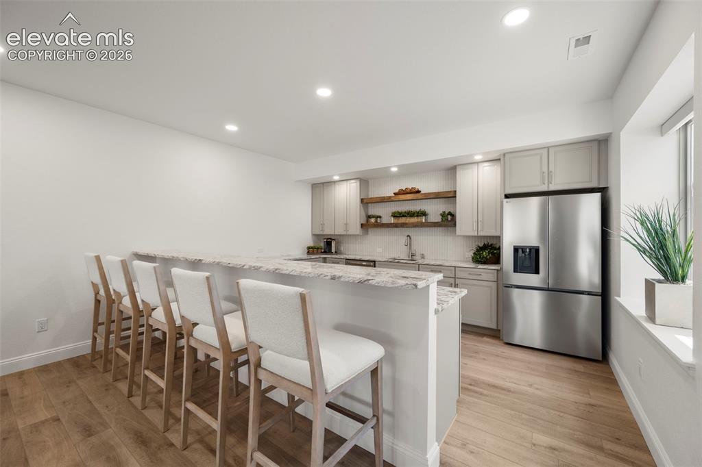 Image 32 of 50: Kitchenette with light wood-finish flooring, light grey cabinetry, stainles