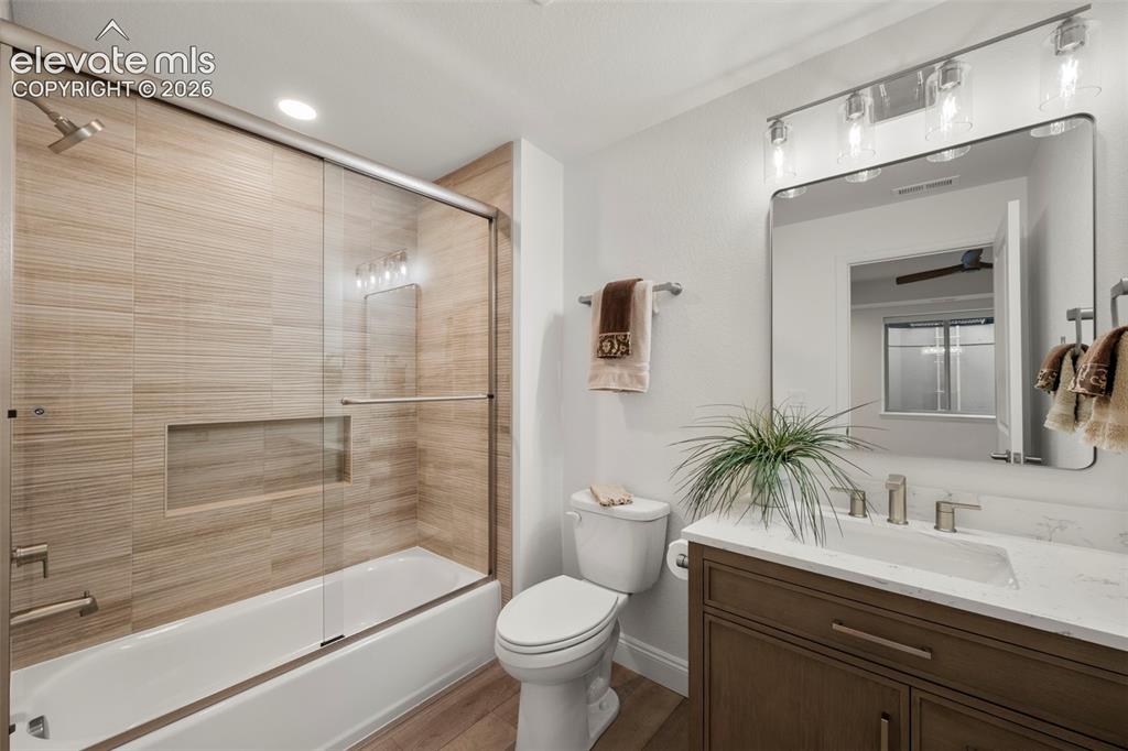 Image 36 of 50: Bathroom featuring wood-finish flooring, a built-in tub with glass enclosur